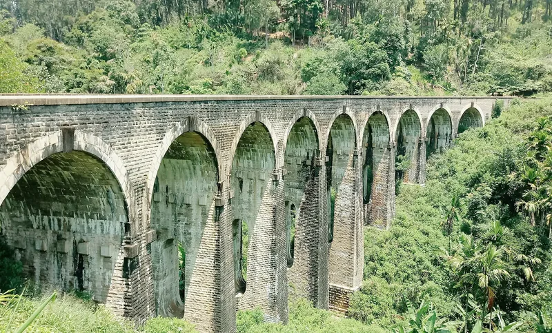 Nine Arch Bridge curving through the green hills of Ella